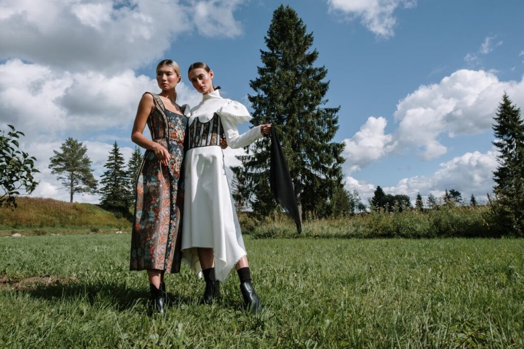 Two stylish women in elegant outfits posing outdoors in a scenic landscape.
